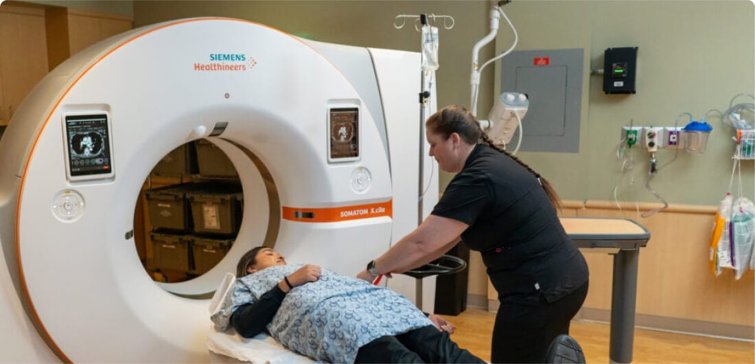 Technologist assisting patient on Siemens Healthineers CT scanner representing Naples medical imaging solutions and equipment service.